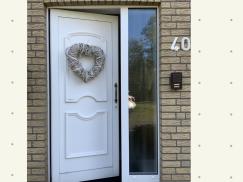 Haustür in weiß mit Glas-Seitenteil und herzförmigem Kranz