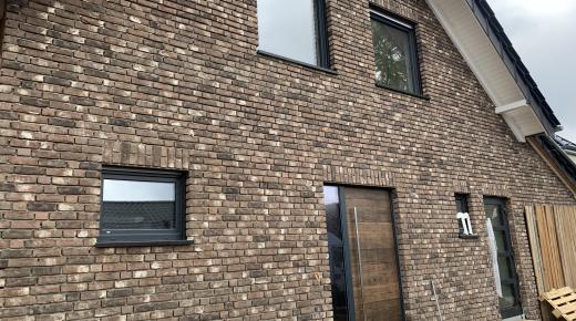 Steinhaus mit Haustür mit Holzverkleidung und Glas-Seitenteil