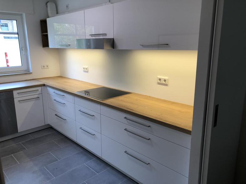 Küche in weiß mit Holzarbeitsplatte und Beleuchtung