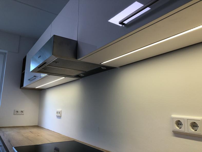 Küche mit Holzarbeitsplatte und Hängeschränken mit Beleuchtung